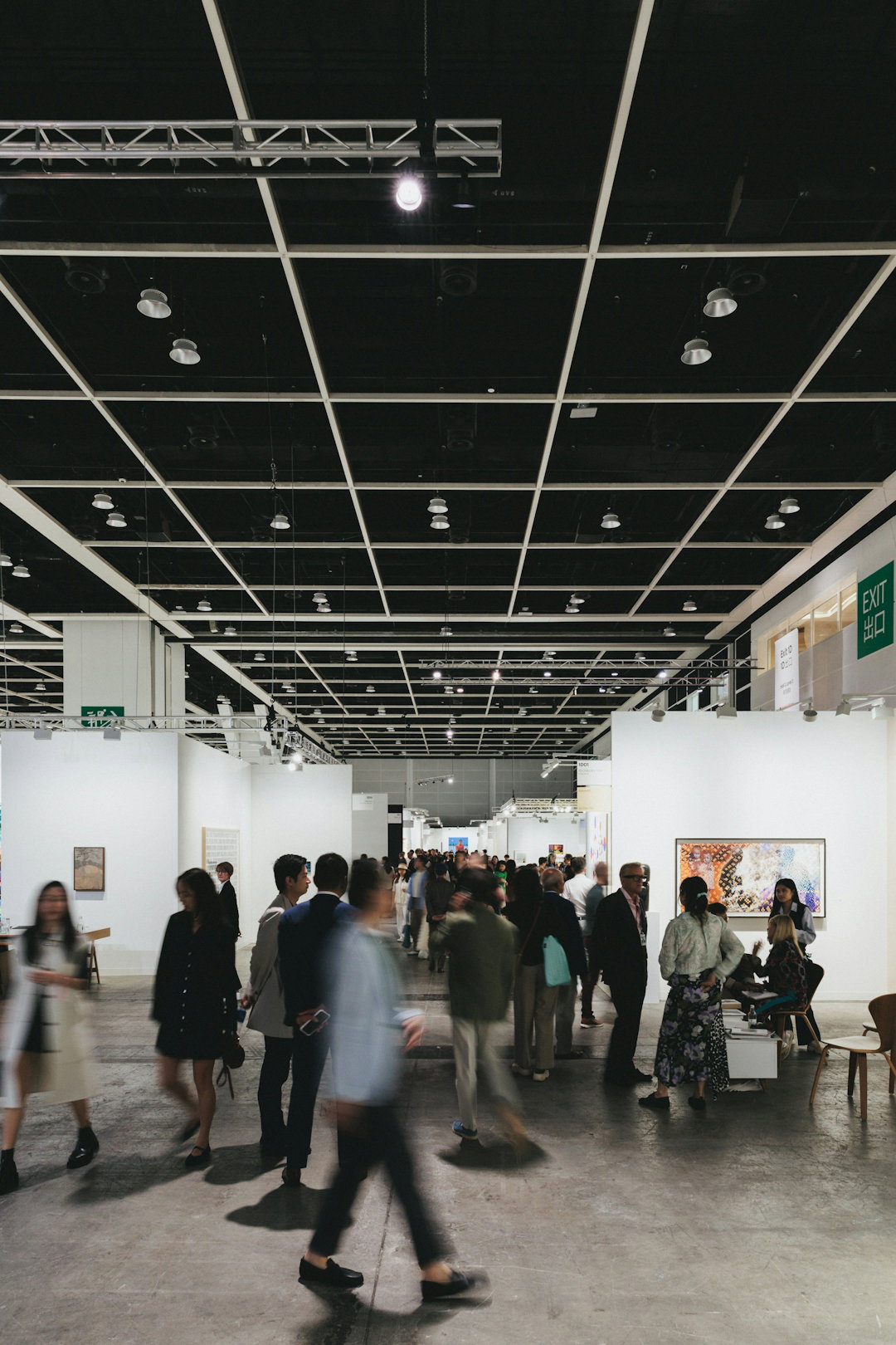 People are walking through a large art gallery.